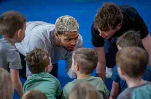 Two grand valley students interact with a group of small children.