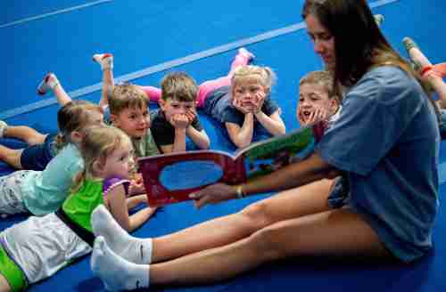 A grand valley student reads a book to a group of small children. 