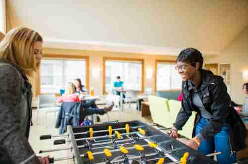 Students play foosball in a living center lounge