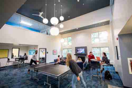 Students chat, play ping pong and study in a lounge space