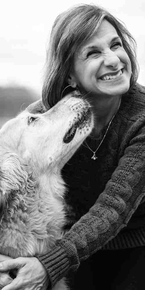 Dottie smiles while her dog sniffs her cheek