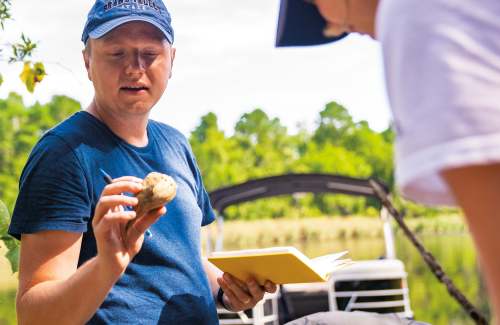 A person holds a rock and shows another person