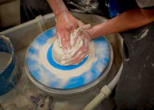 Student throws clay on a pottery wheel