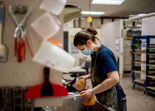 Student holds ceramic pieces by a sink in the ceramic studio