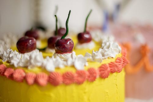 A bright yellow and orange clay 'cake' with whipped cream and cherries