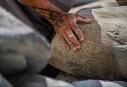 Artist Jason Quigno lays his hand on a stone