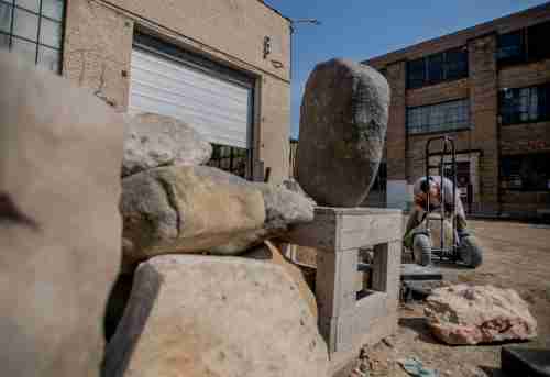 Artist Jason Quigno works with stones outside of his studio