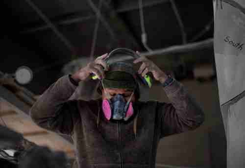 Artist Jason Quigno puts on a protective mask in his studio