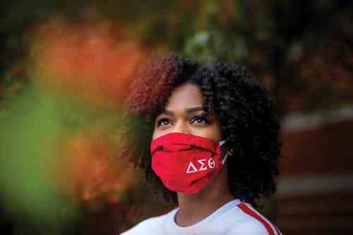 Student wearing a red mask with sorority symbols on it