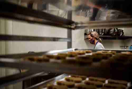 A cart of baked cookies and a person working in the background
