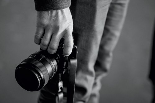 A close up black and white photo of a hand holding a camera