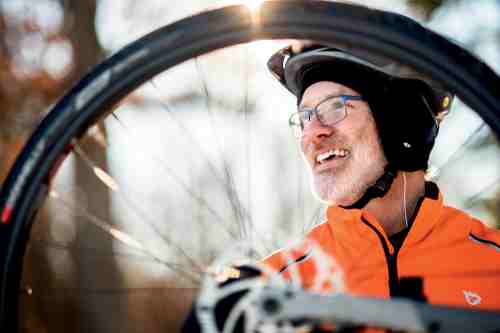 Man smiles with bike wheel