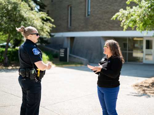 Colleen Bailey stands in front of a living center and talks to a police officer