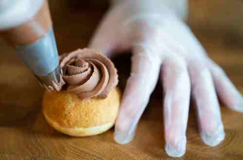 Close up of hands frosting a small pastry