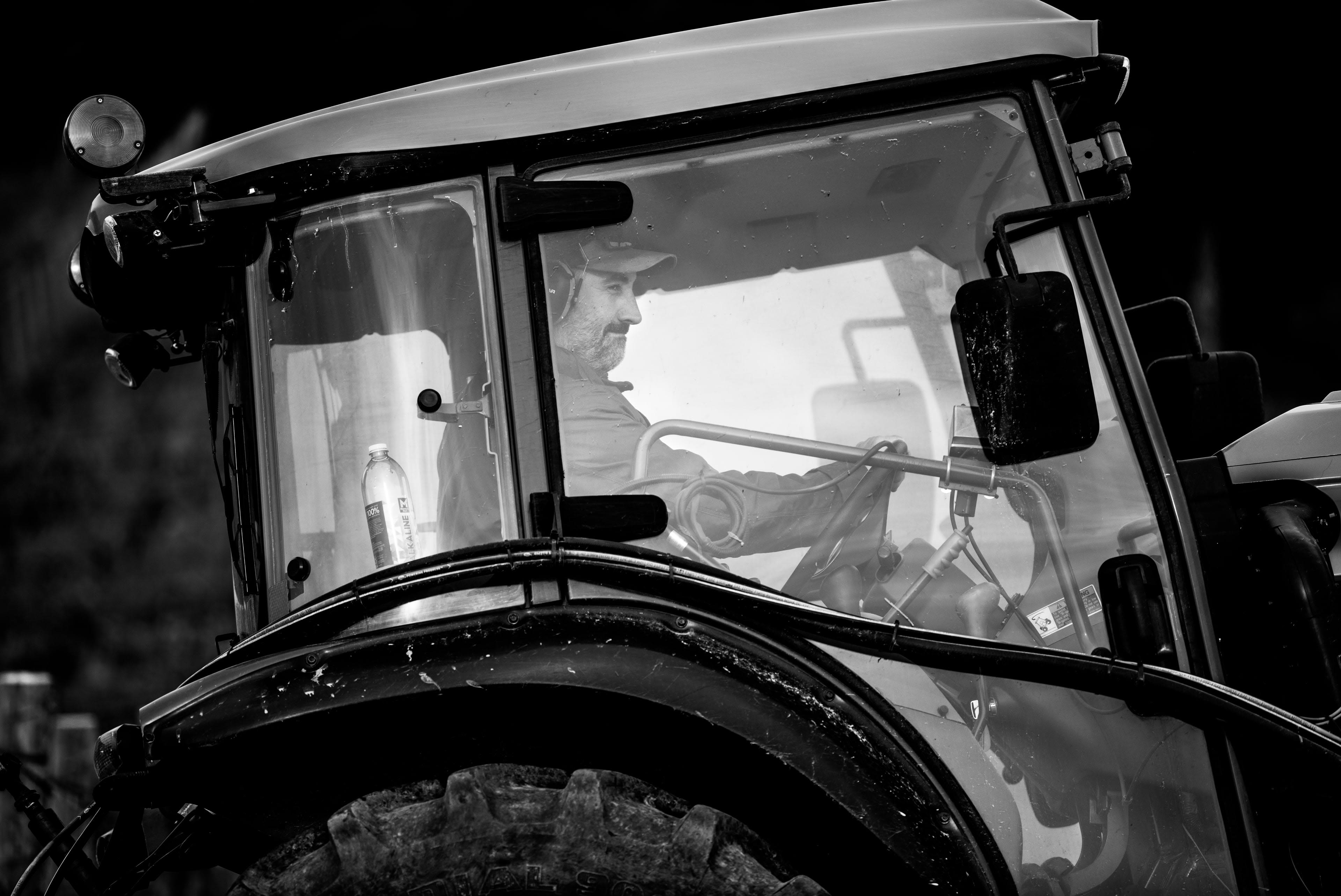 A black and white photo of a man driving a tractor