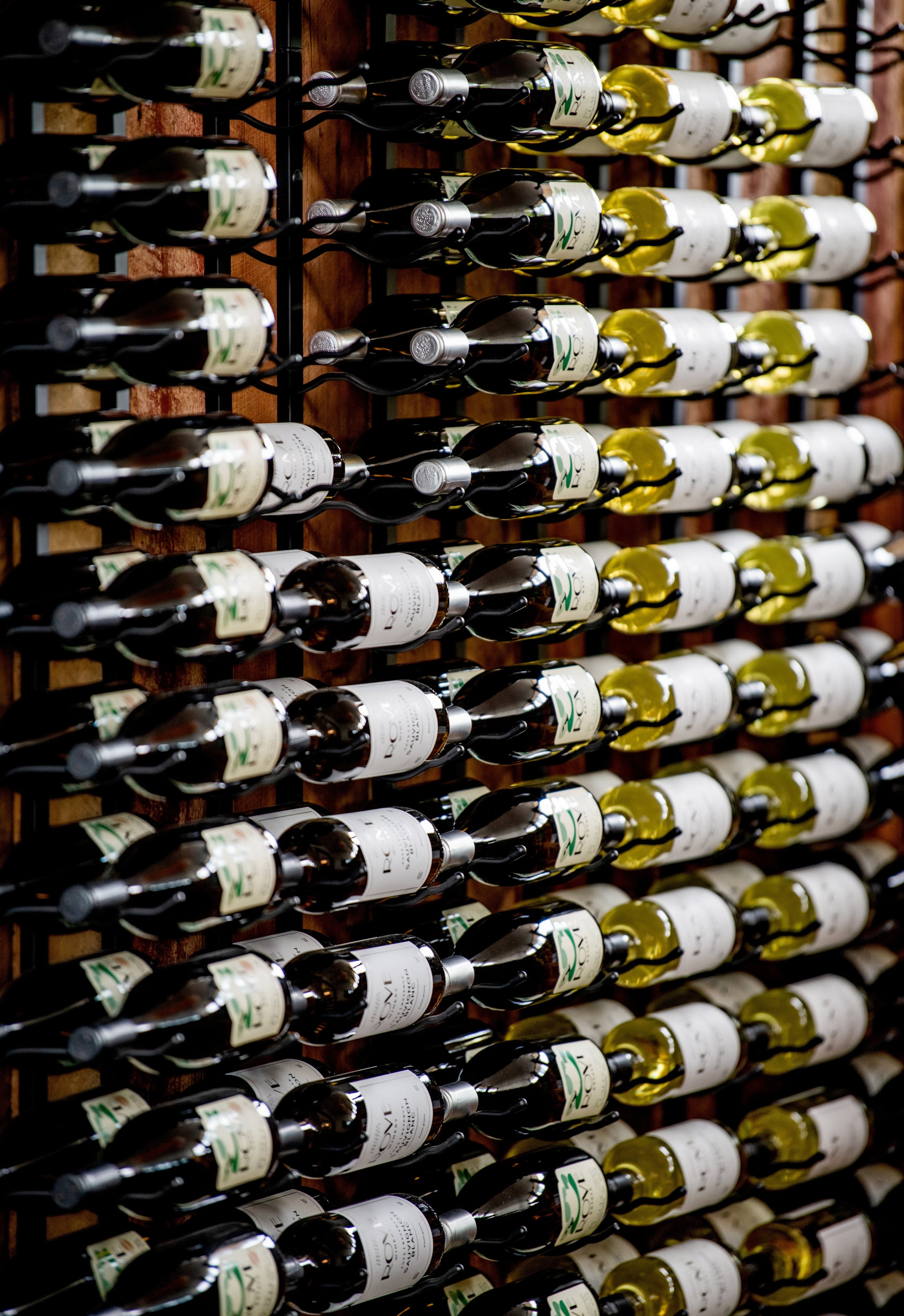 A wall of wine bottles neatly displayed, half red and half white wine