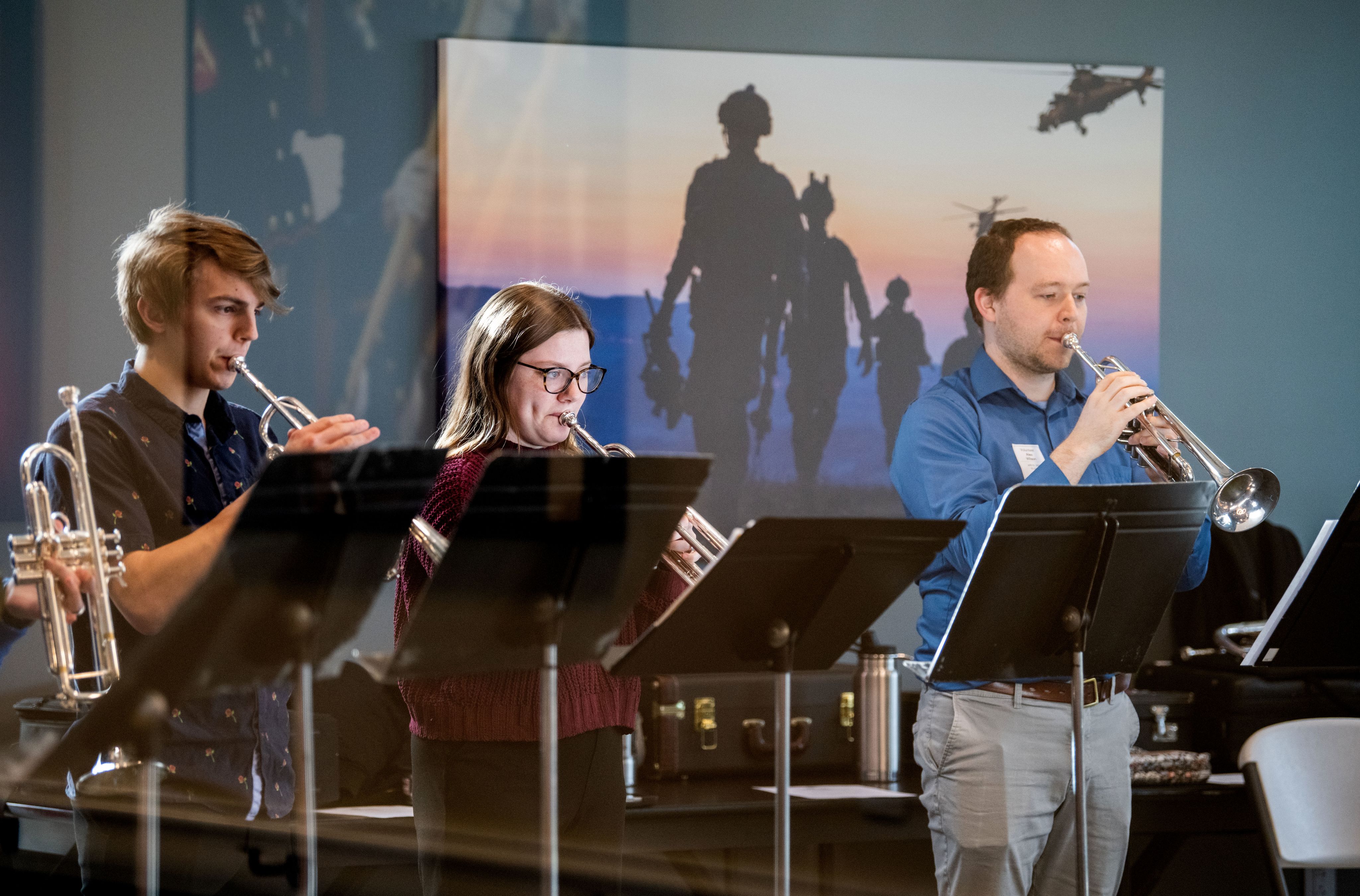 members of a trumpet ensemble stand and perform at a veterans home