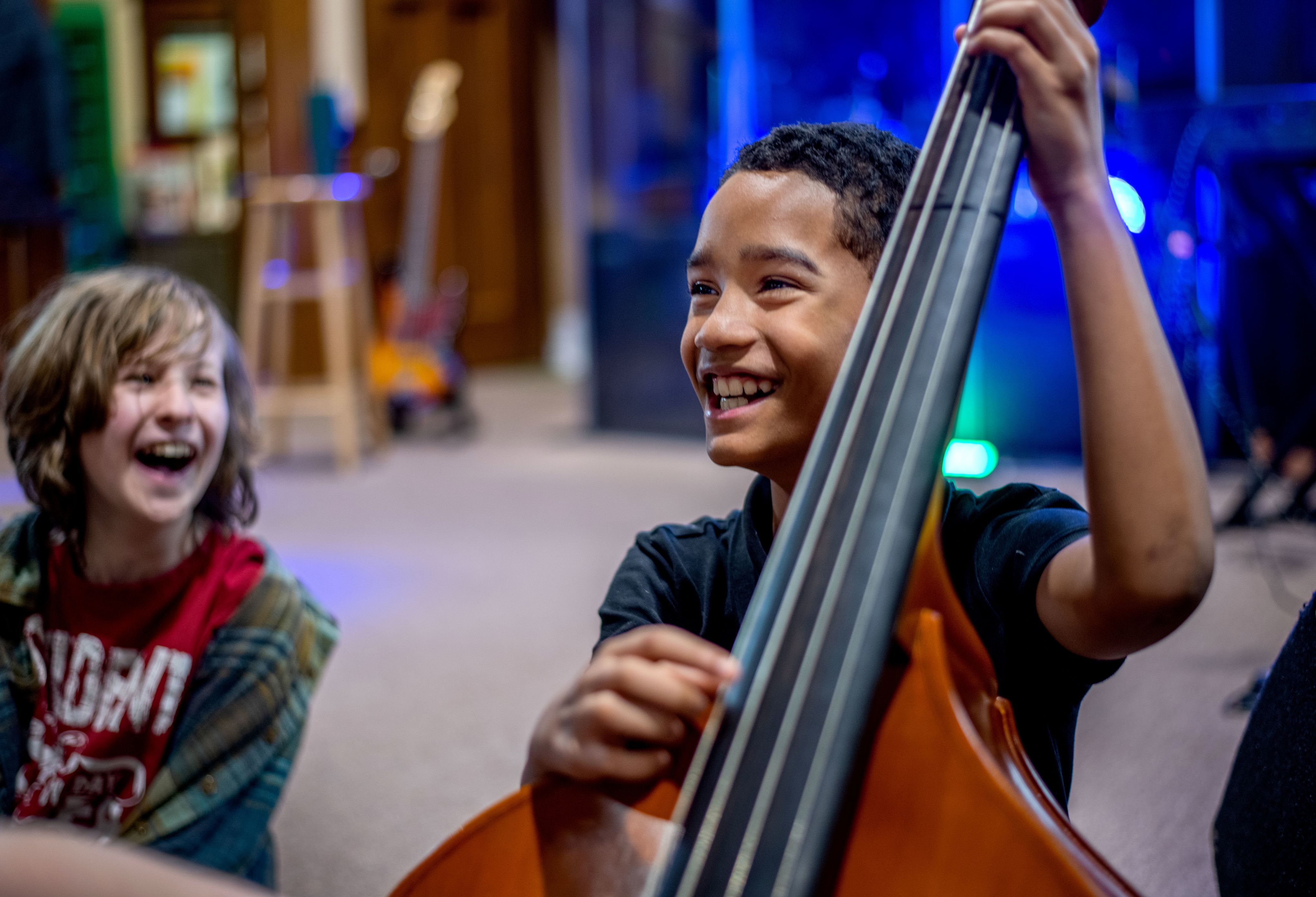young student plucks a bass while seated on floor
