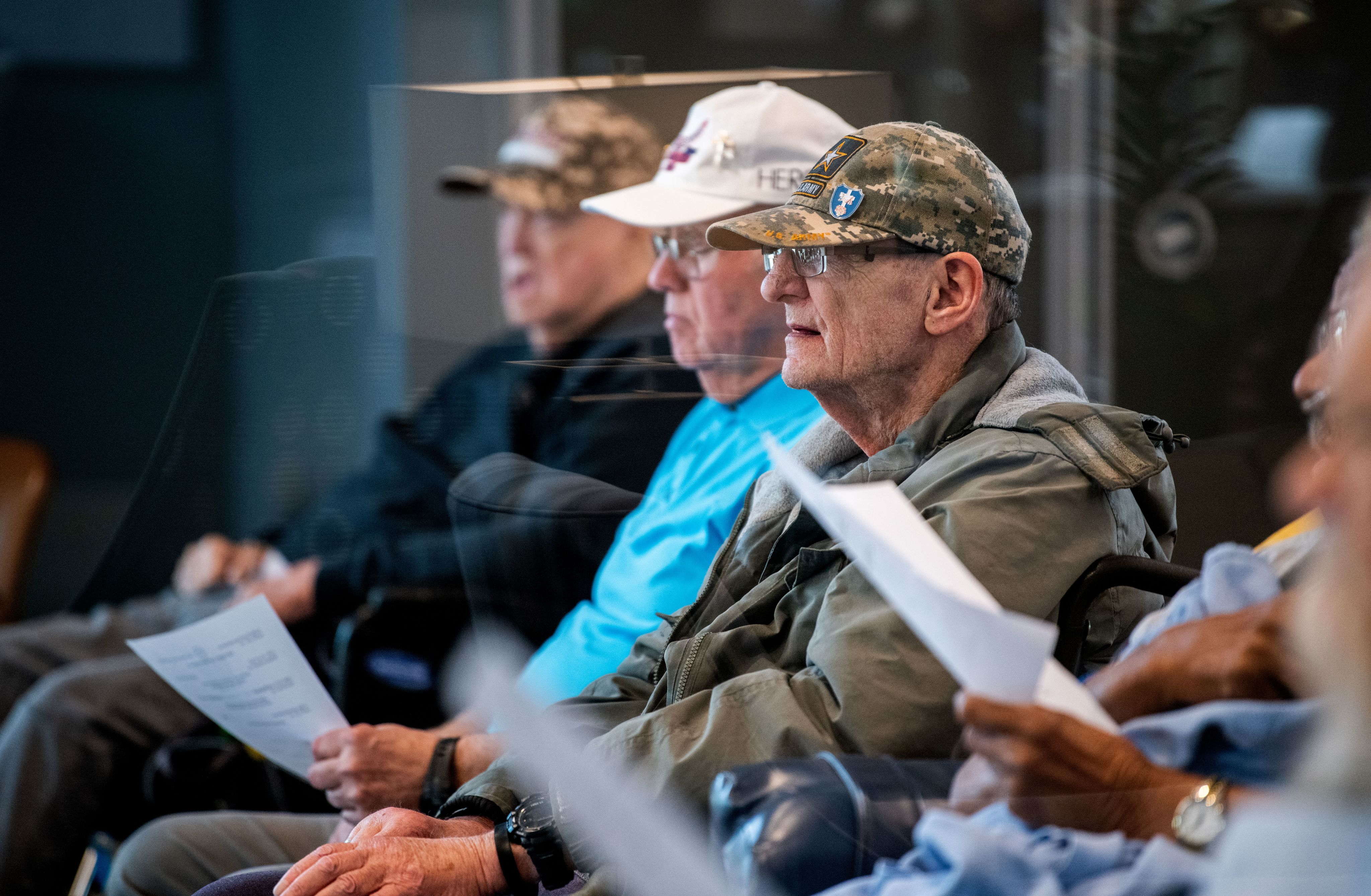 Men in baseball caps sit down for a concert at the Michigan Veteran Homes at Grand Rapids