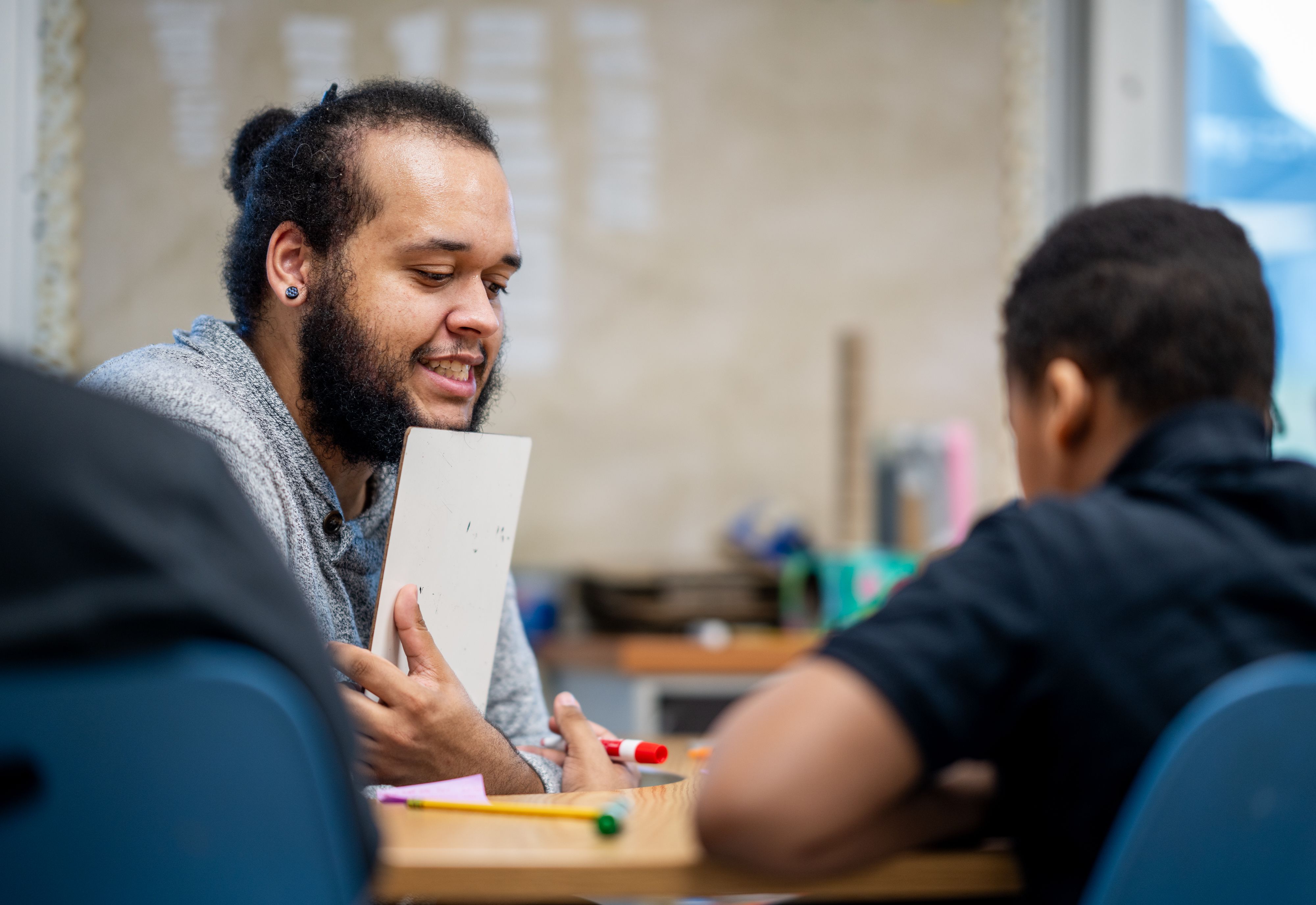 Devan Washington chats with a student while holding a tablet