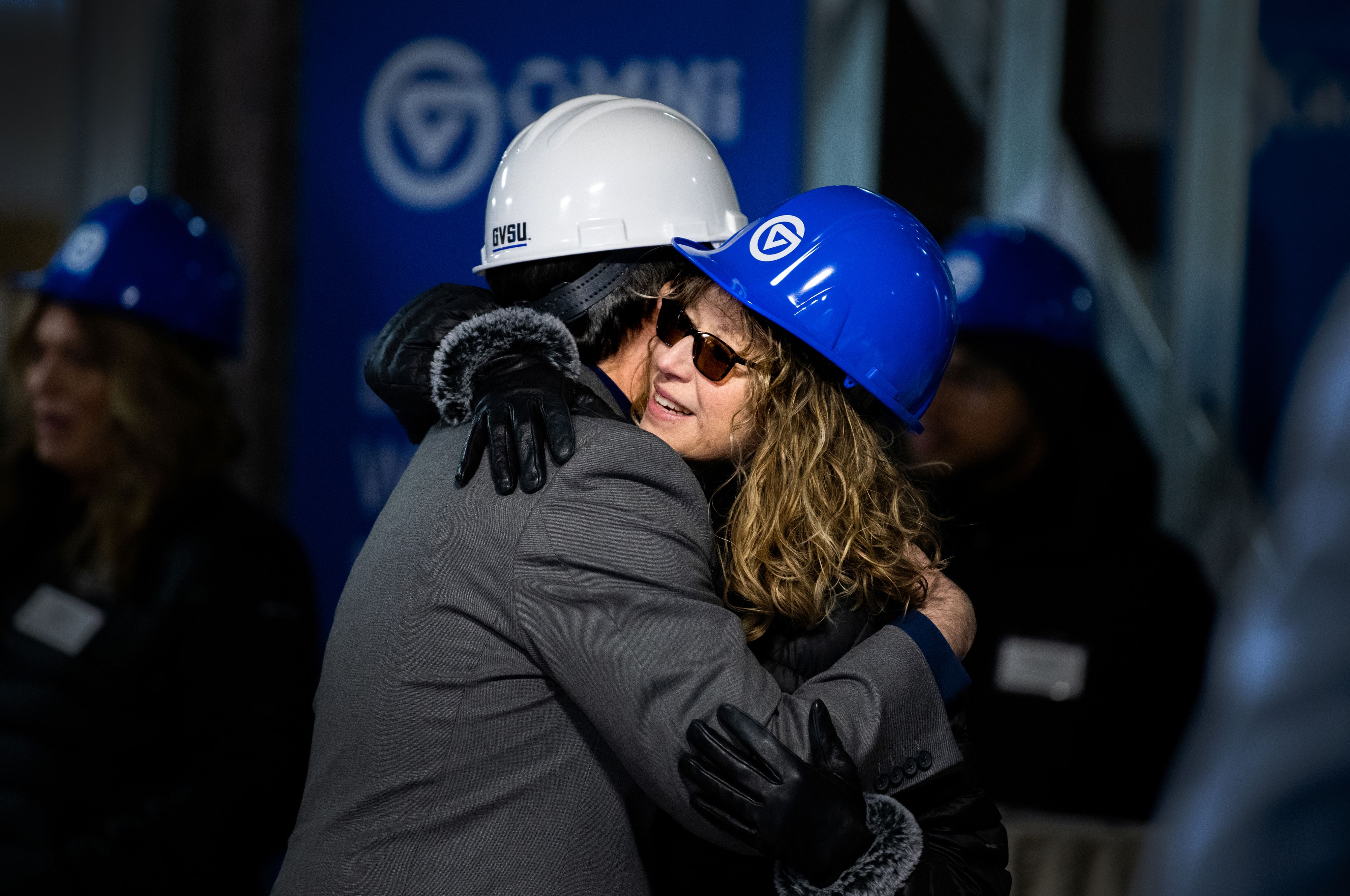 two people in hard hats embrace during a tour of a construction site