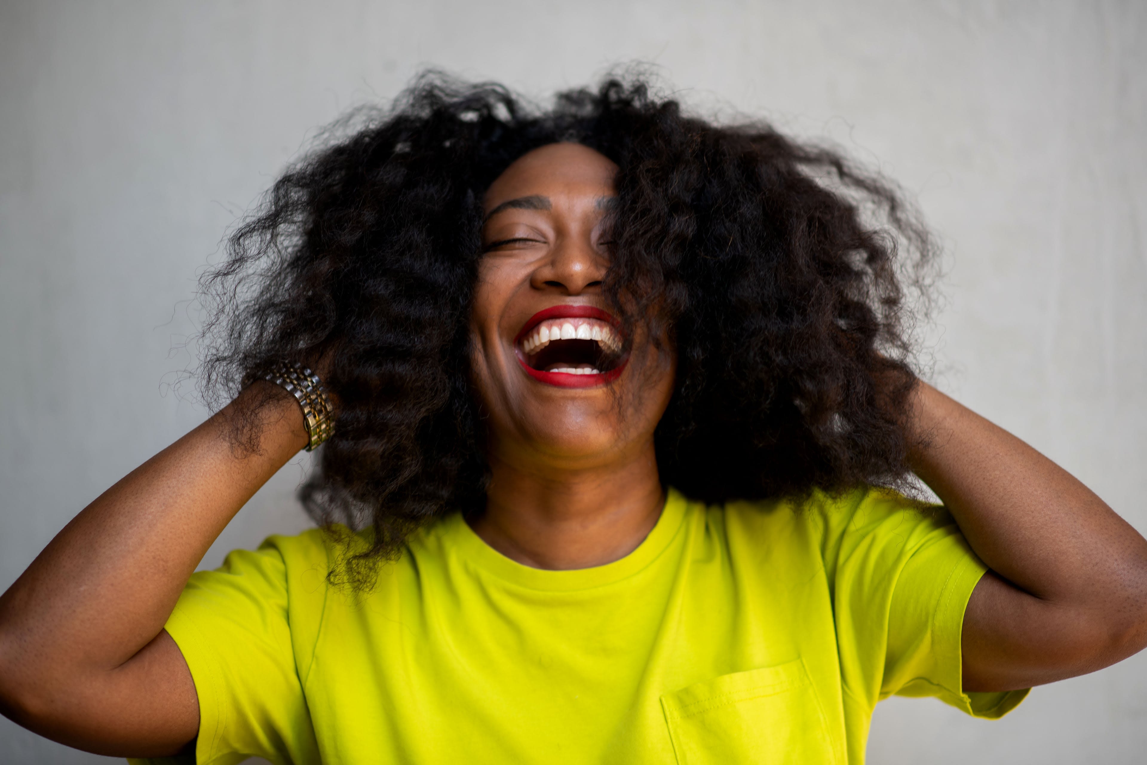 Andrea Wallace in yellow tshirt with headphones on, smiling; blue and purple background
