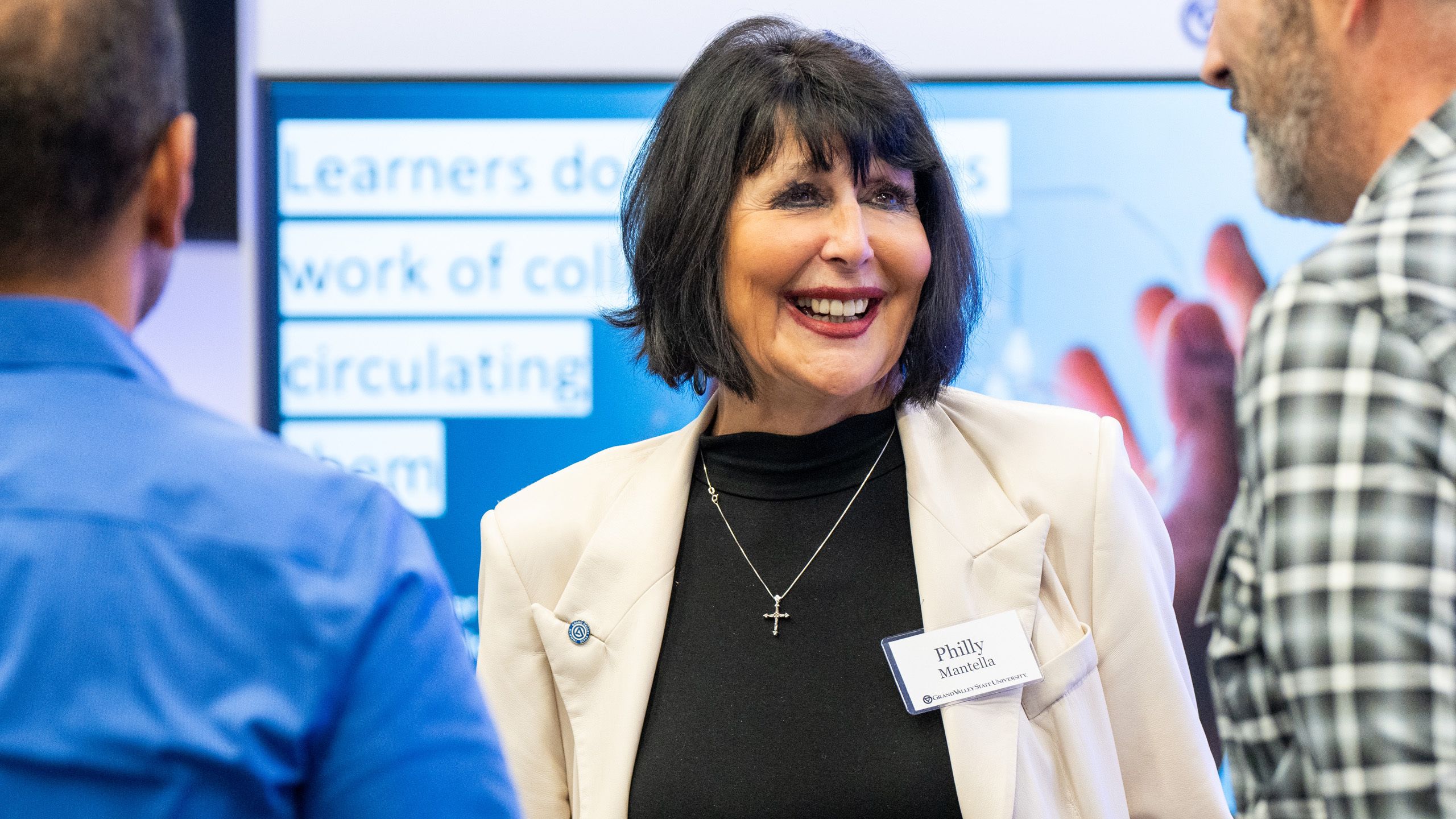 President Mantella in center of three people, chatting, wearing a light jacket and dark shirt