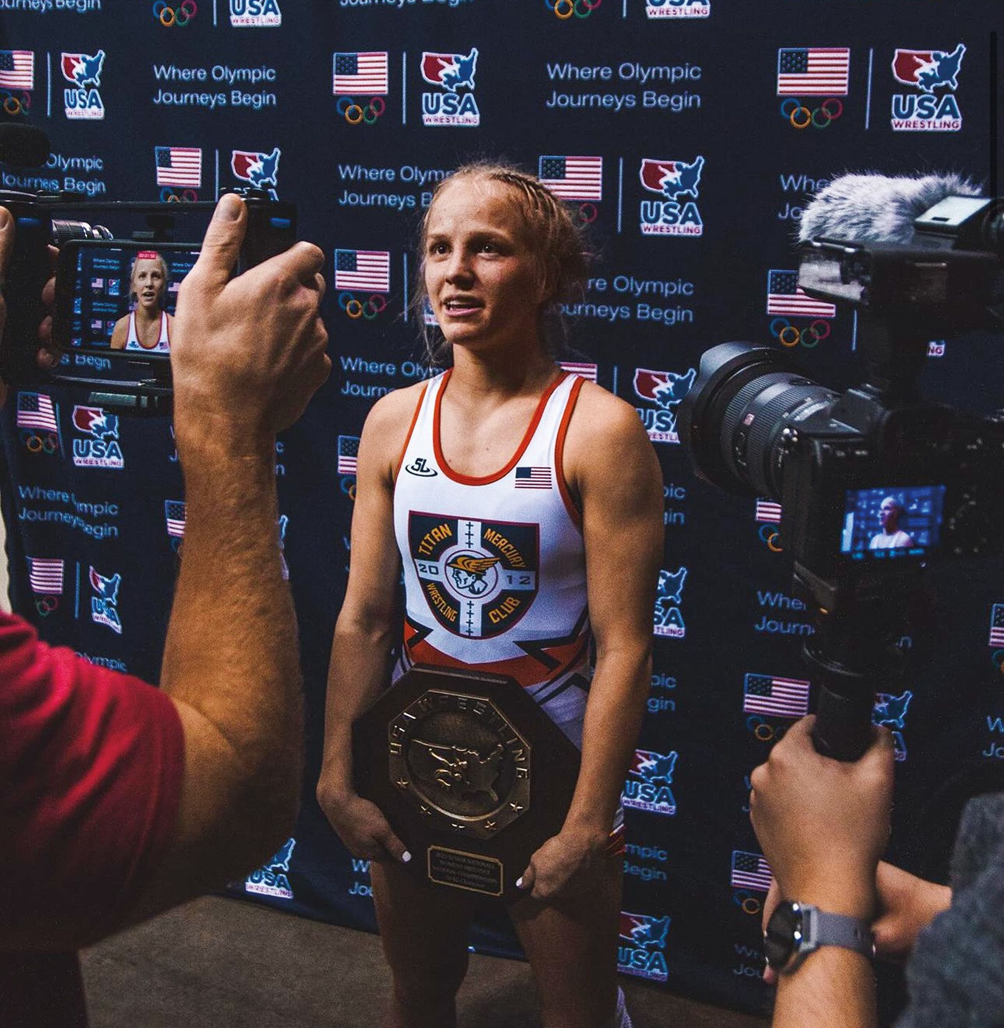 cameras pointed at young woman in white wrestling singlet