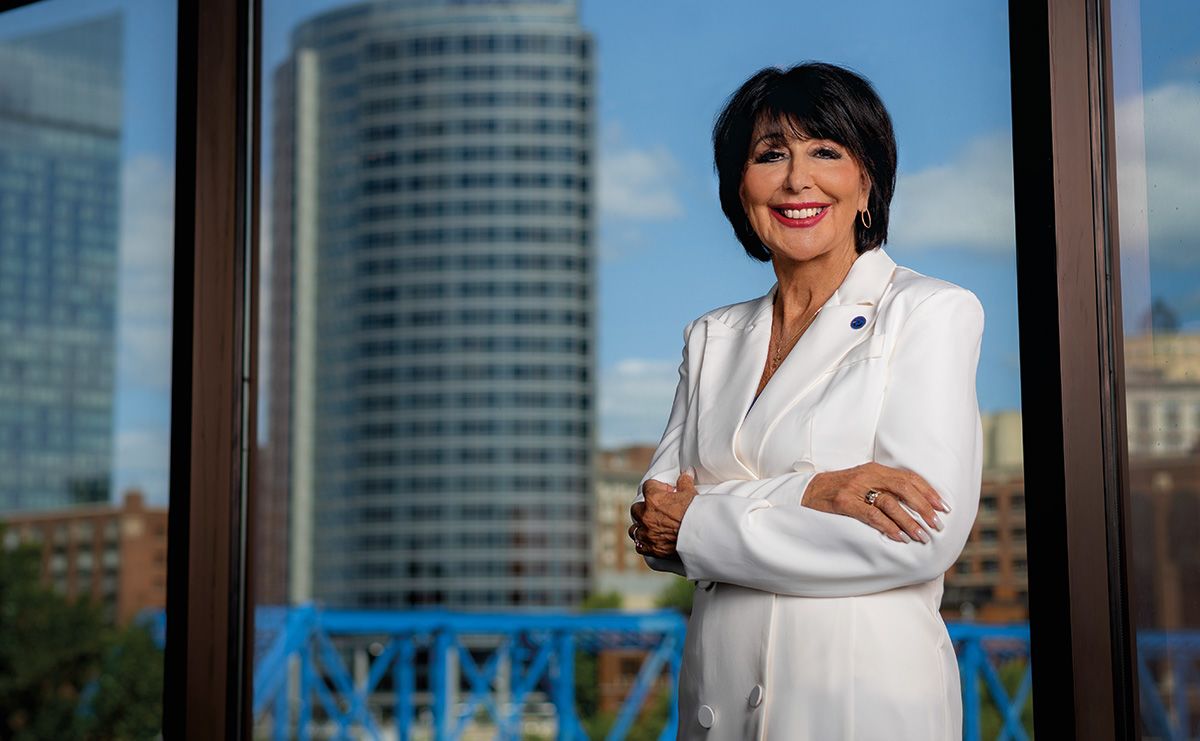 President Mantella in white jacket against window showing skyline of Grand Rapids