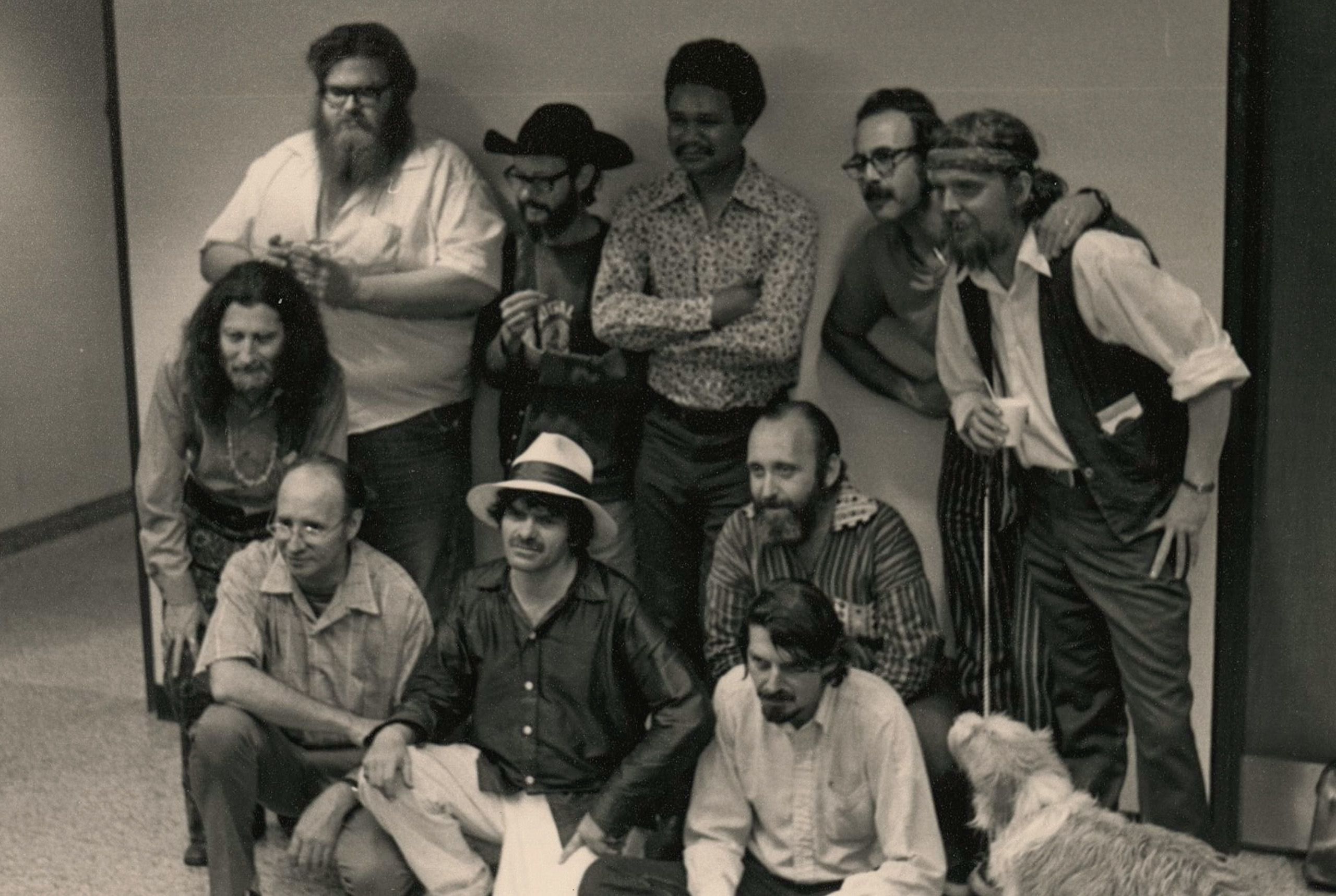 group of 10 men, five kneeling five standing, one dog in this 1970s era black and white photo