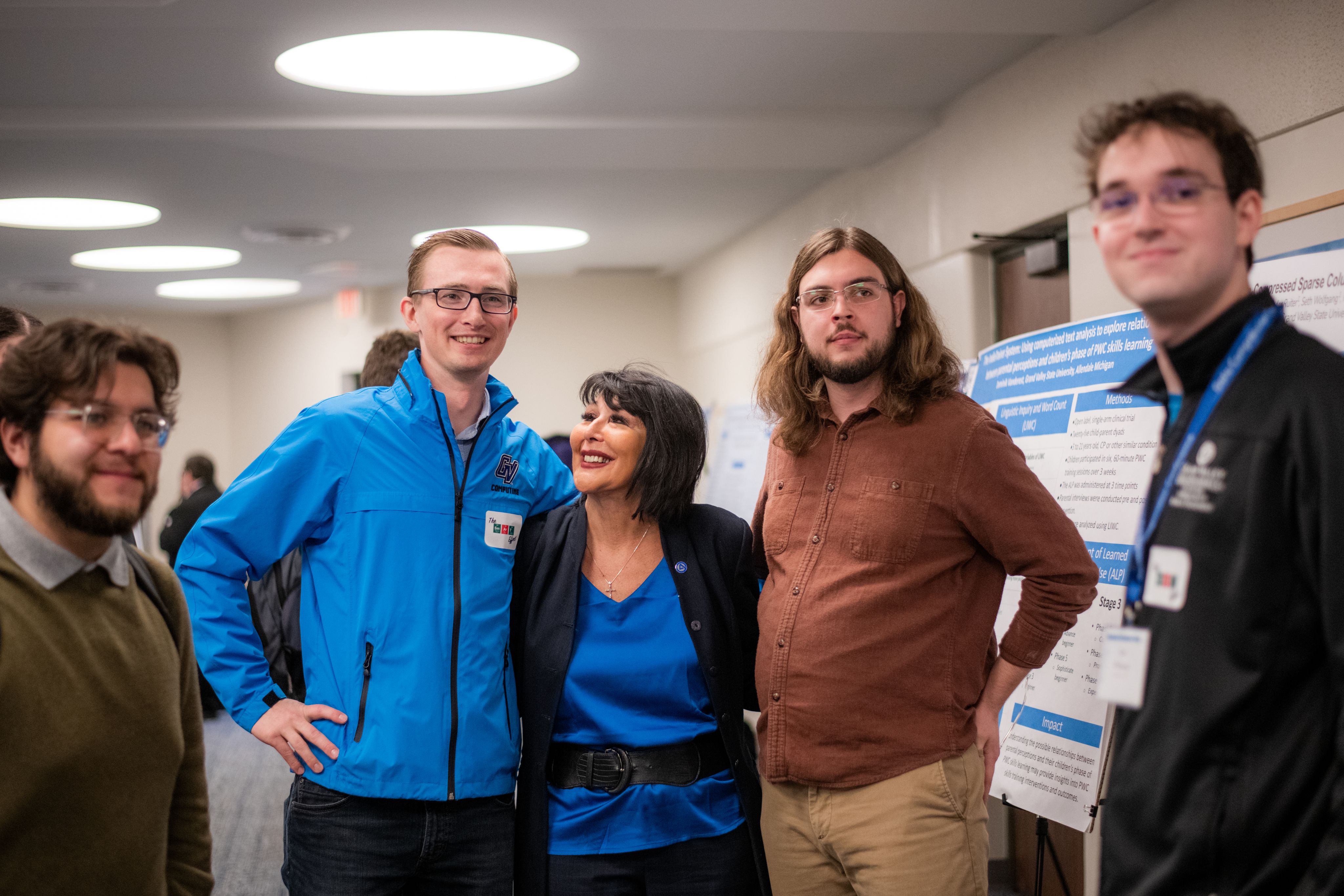 five people, including Zach DeBruine in light blue jacket and President Mantella standing next to a poster presentation