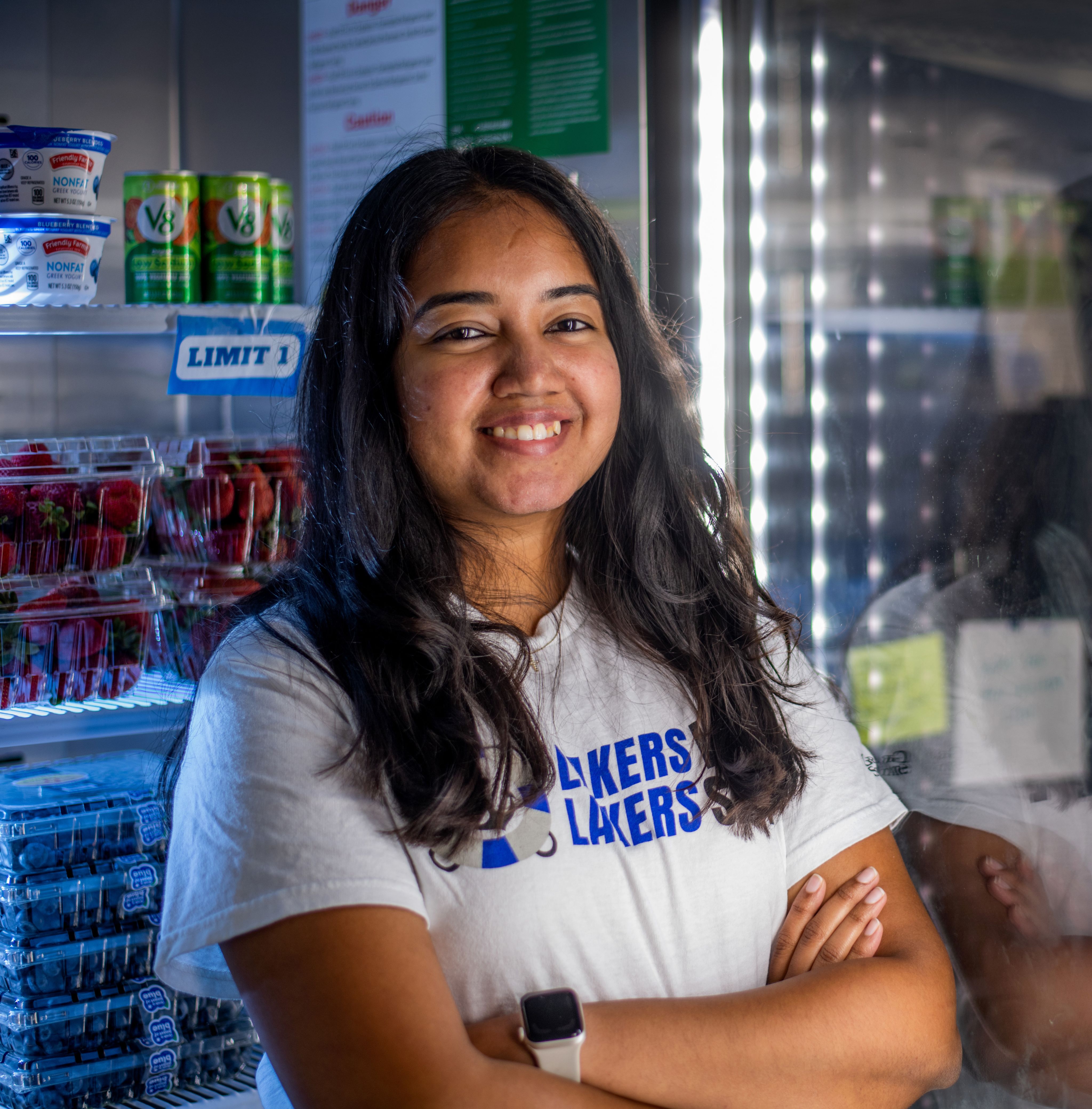 student stands with arms crossed in front of refrigerator