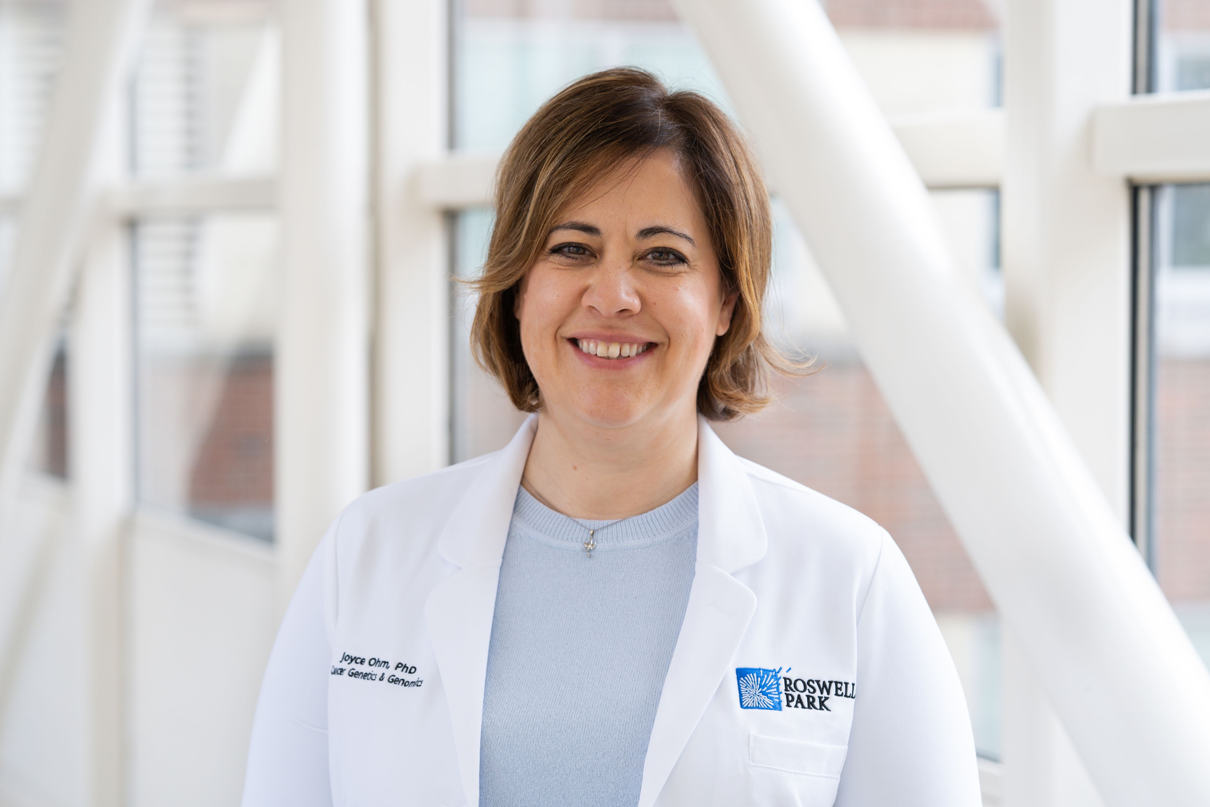 Joyce Ohm in white lab coat, standing near hallway pillars