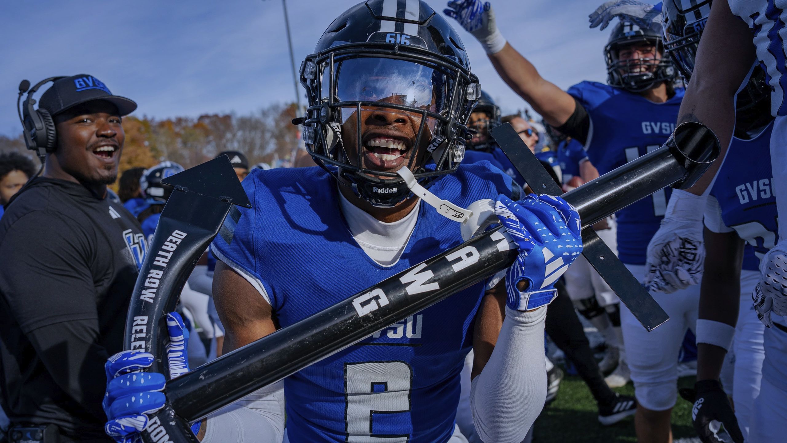 Laker football player holding black pole with DAWG in white letters
