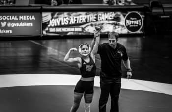 woman wrestler and coach who holds her arm up after she won a match