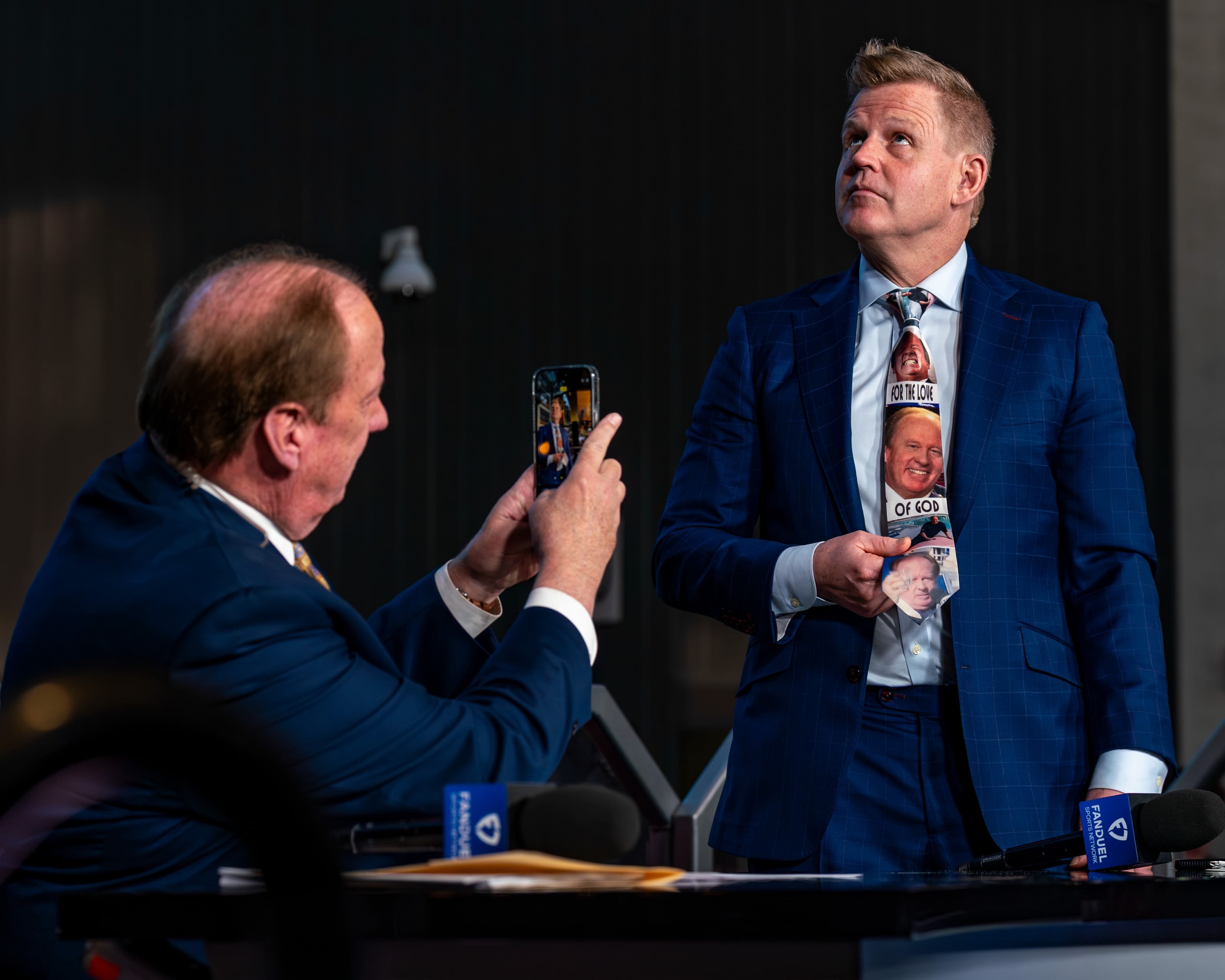 John Keating takes a photo of Chris Osgood while Osgood shows off his tie featuring pictures of Keating's face.