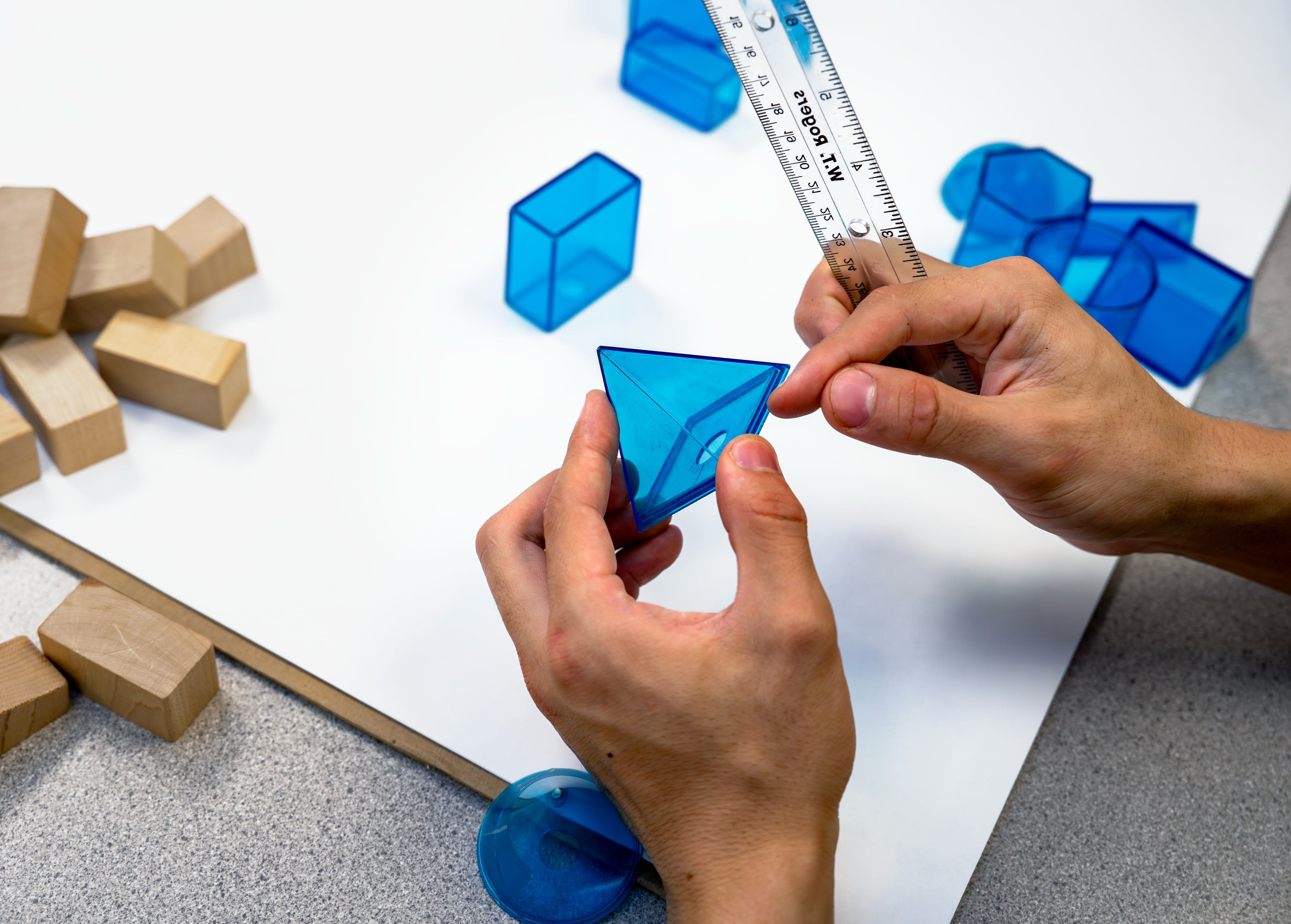 3D shapes in plastic and wood, a plastic ruler scattered on table