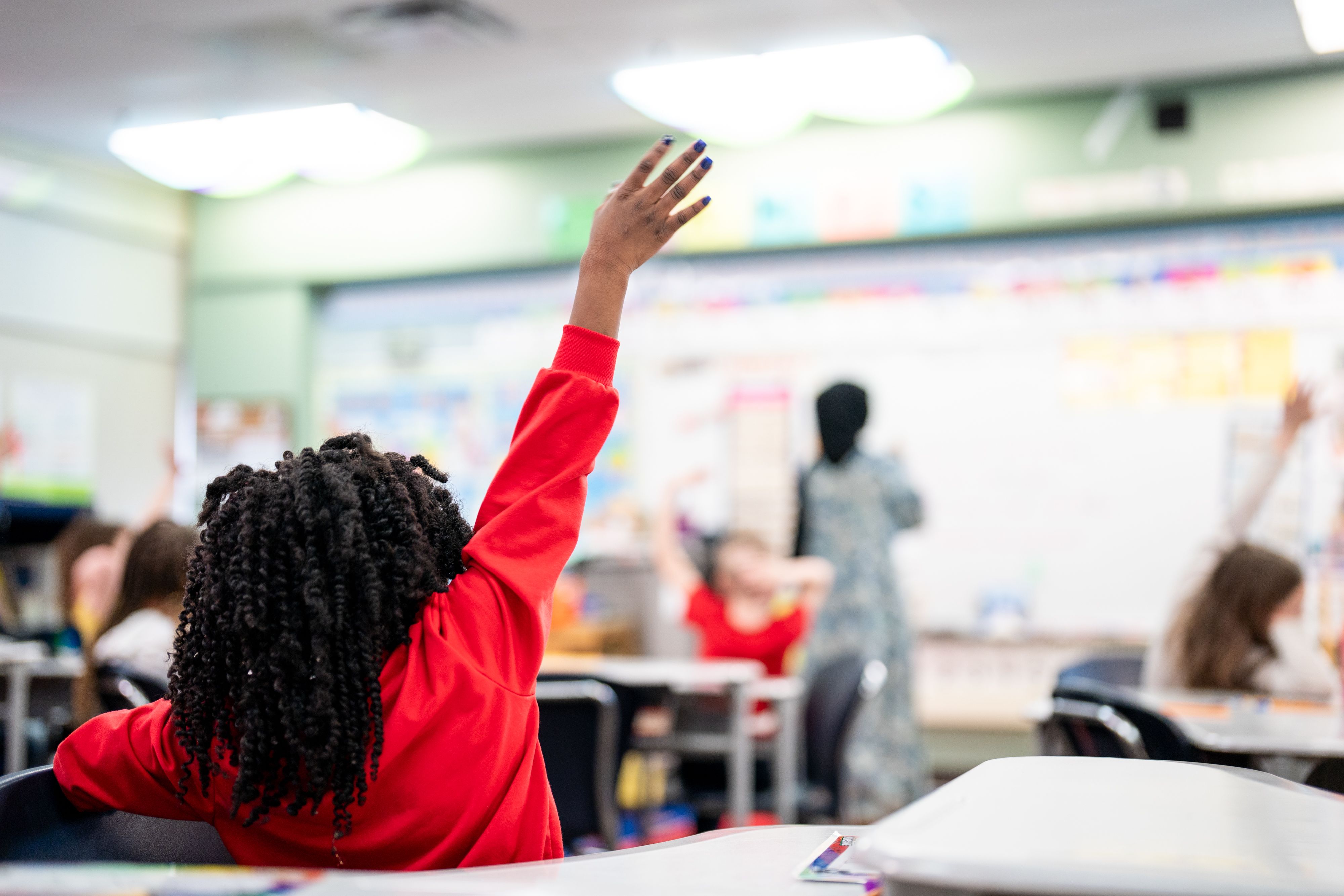 classroom, student in red raises hand