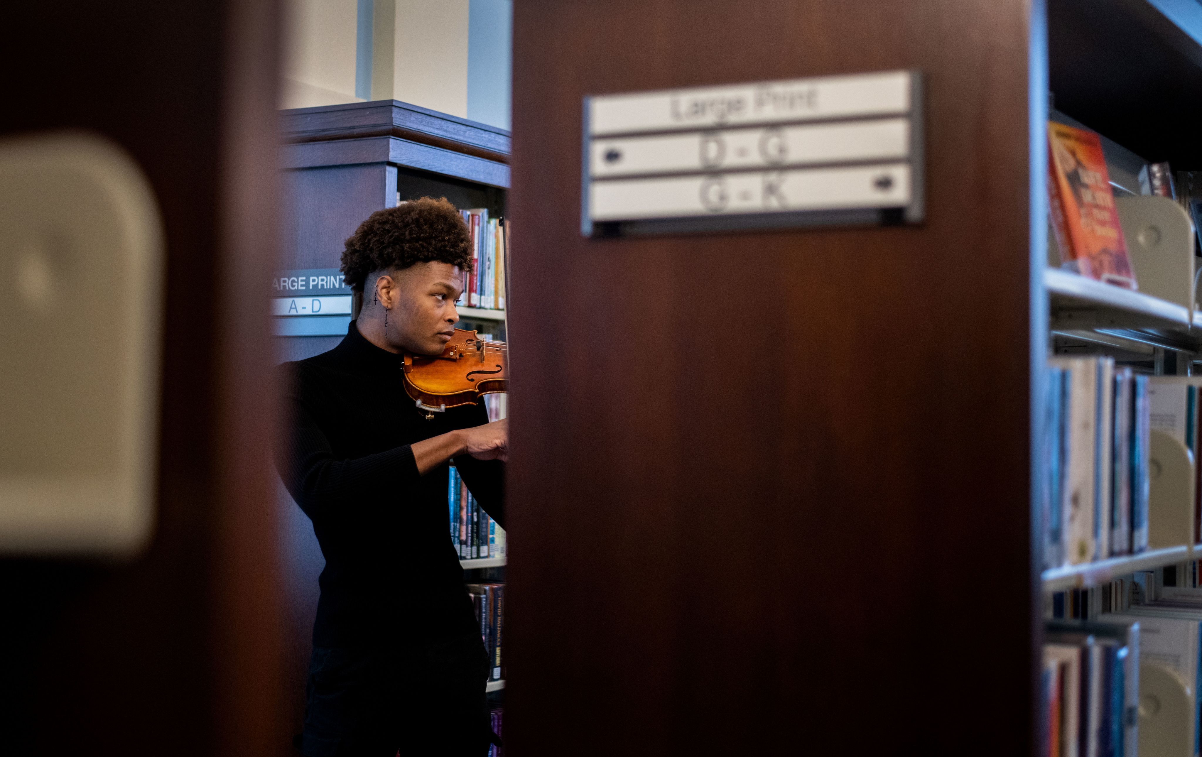 student plays the violin in the library stacks
