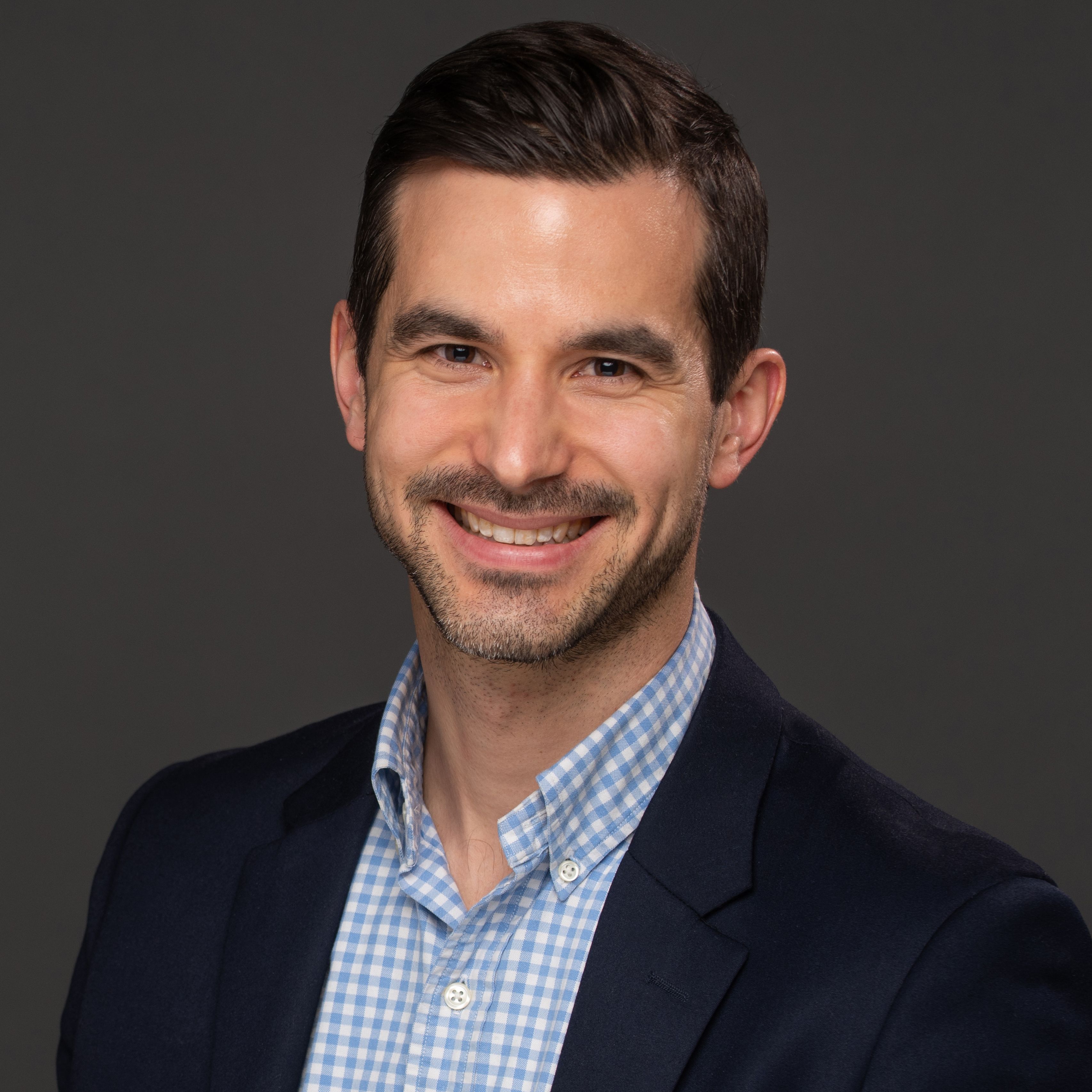 Alex Priebe in blue blazer, checked shirt, smiling