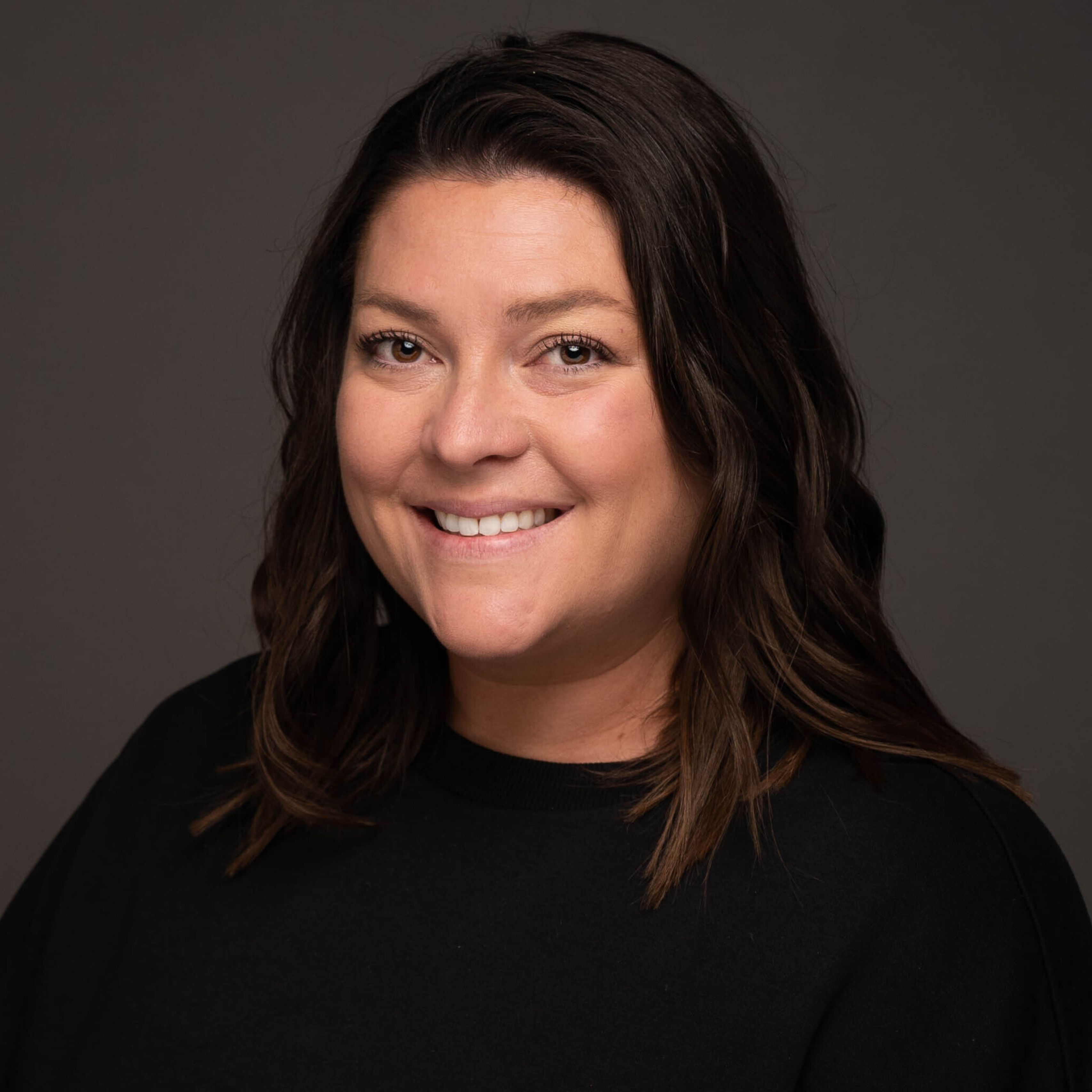 Stephanie Aikens in dark shirt, dark hair, smiling