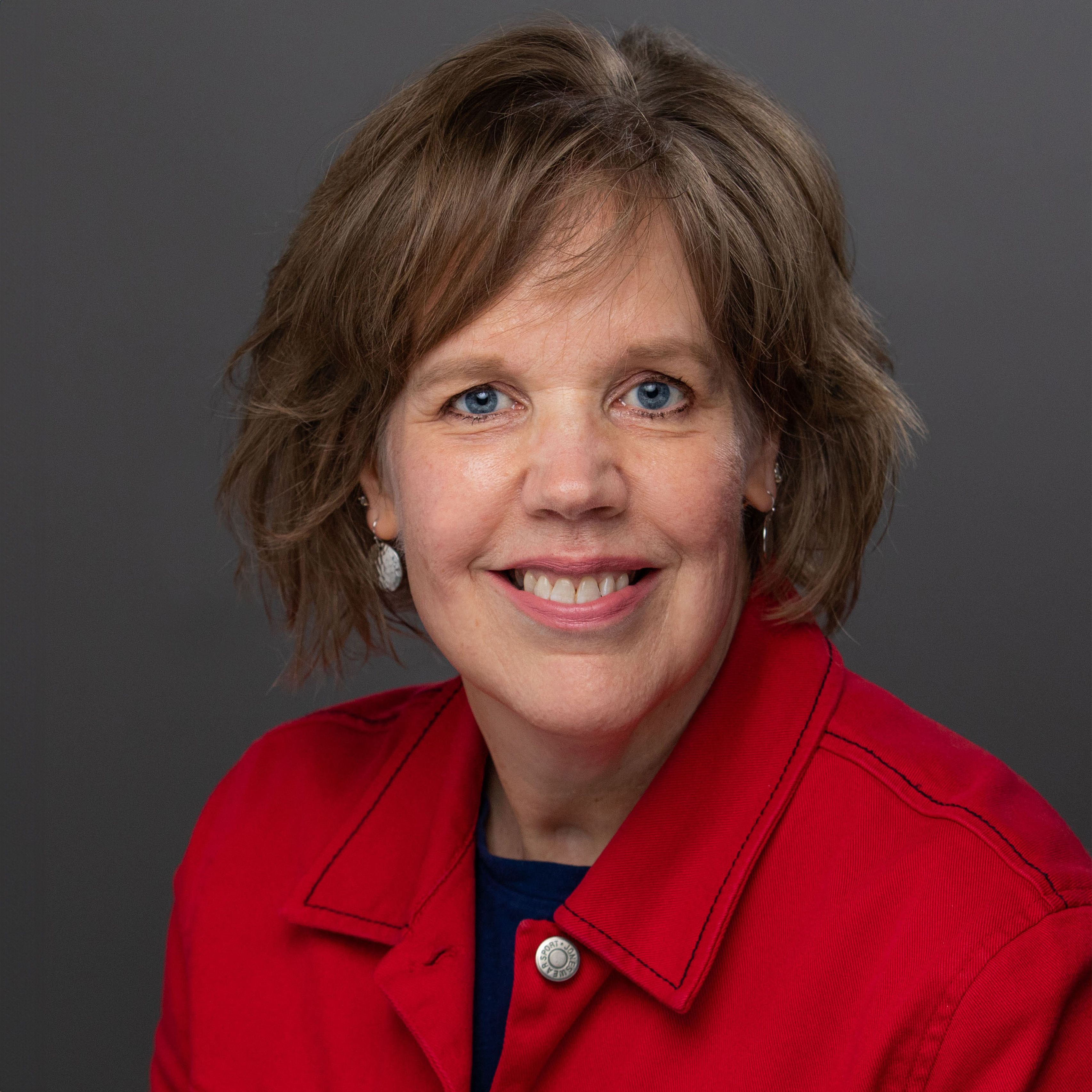 Michele Coffill in red jacket, smiling