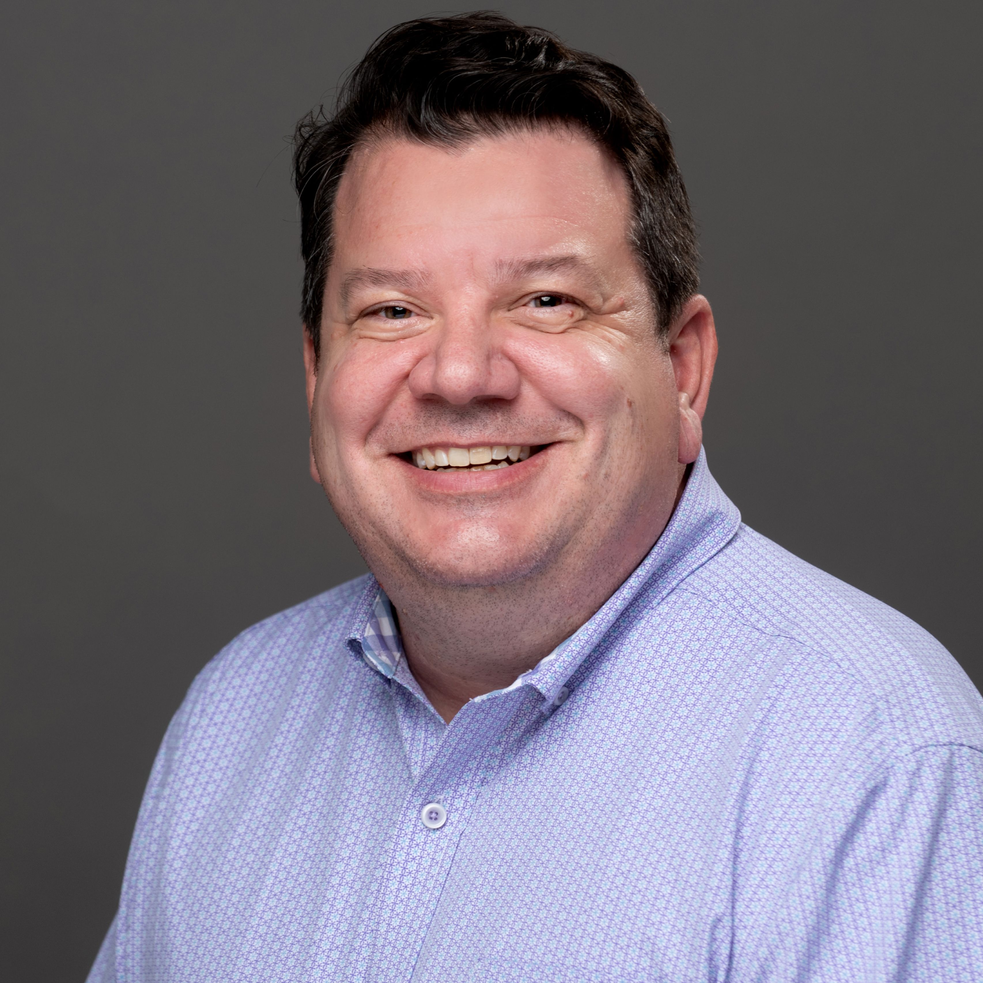 Brian Vernellis in blue shirt, smiling