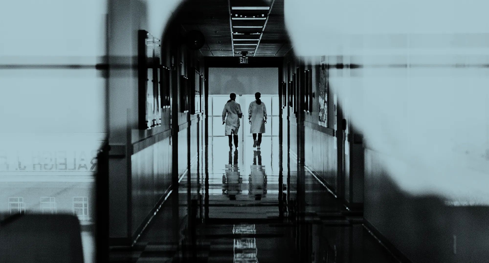 Wearing white lab coats, cell and molecular biology faculty members Pei-Lan Tsou and Sheila Blackman walking down a hall in the Cook-DeVos Center for Health Sciences.