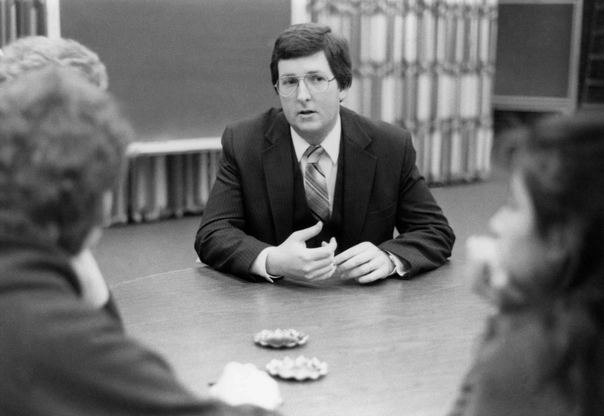 black and white photo of Bob Stoll at center of table