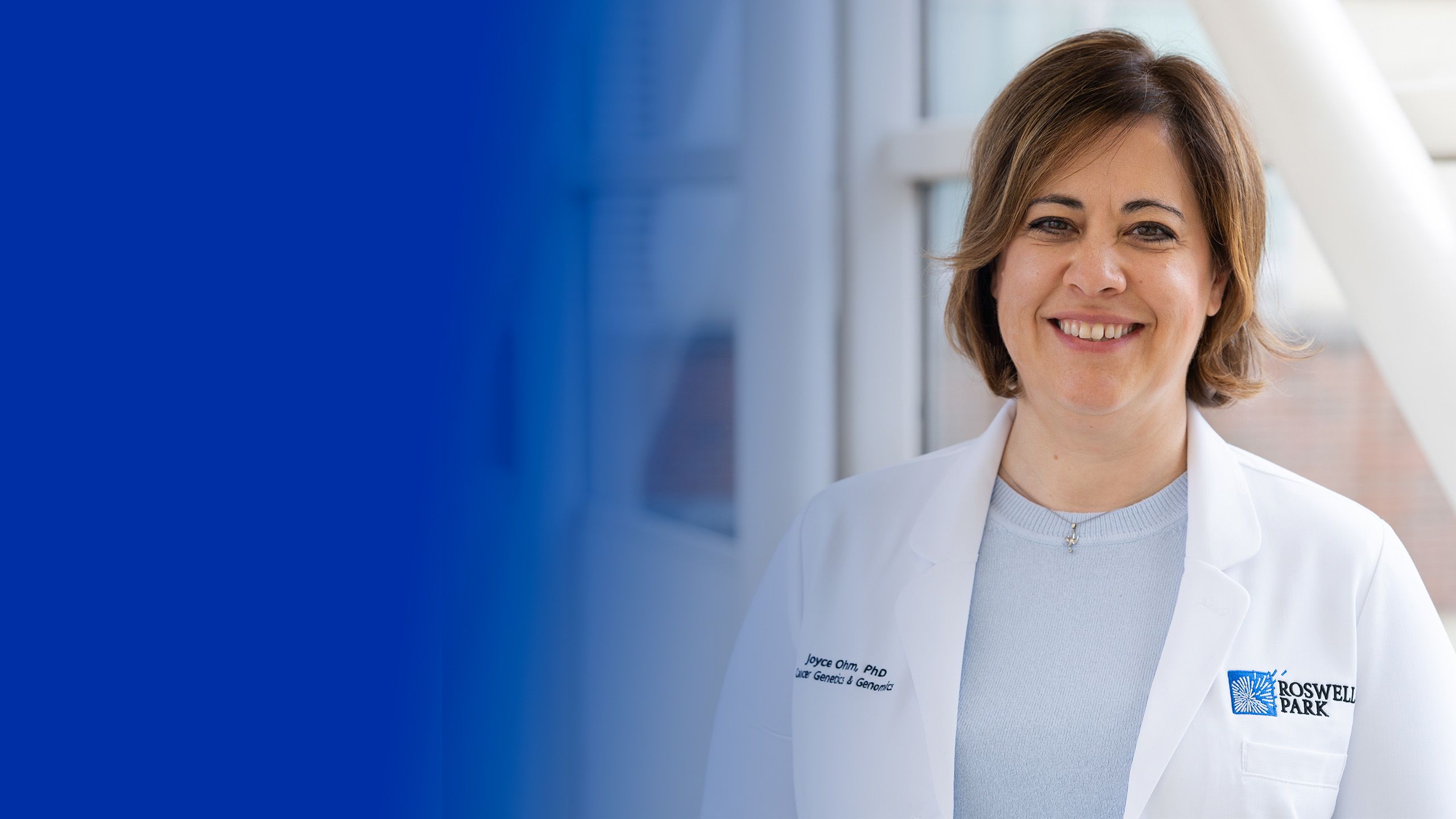 Joyce Ohm in white lab coat, standing near hallway pillars