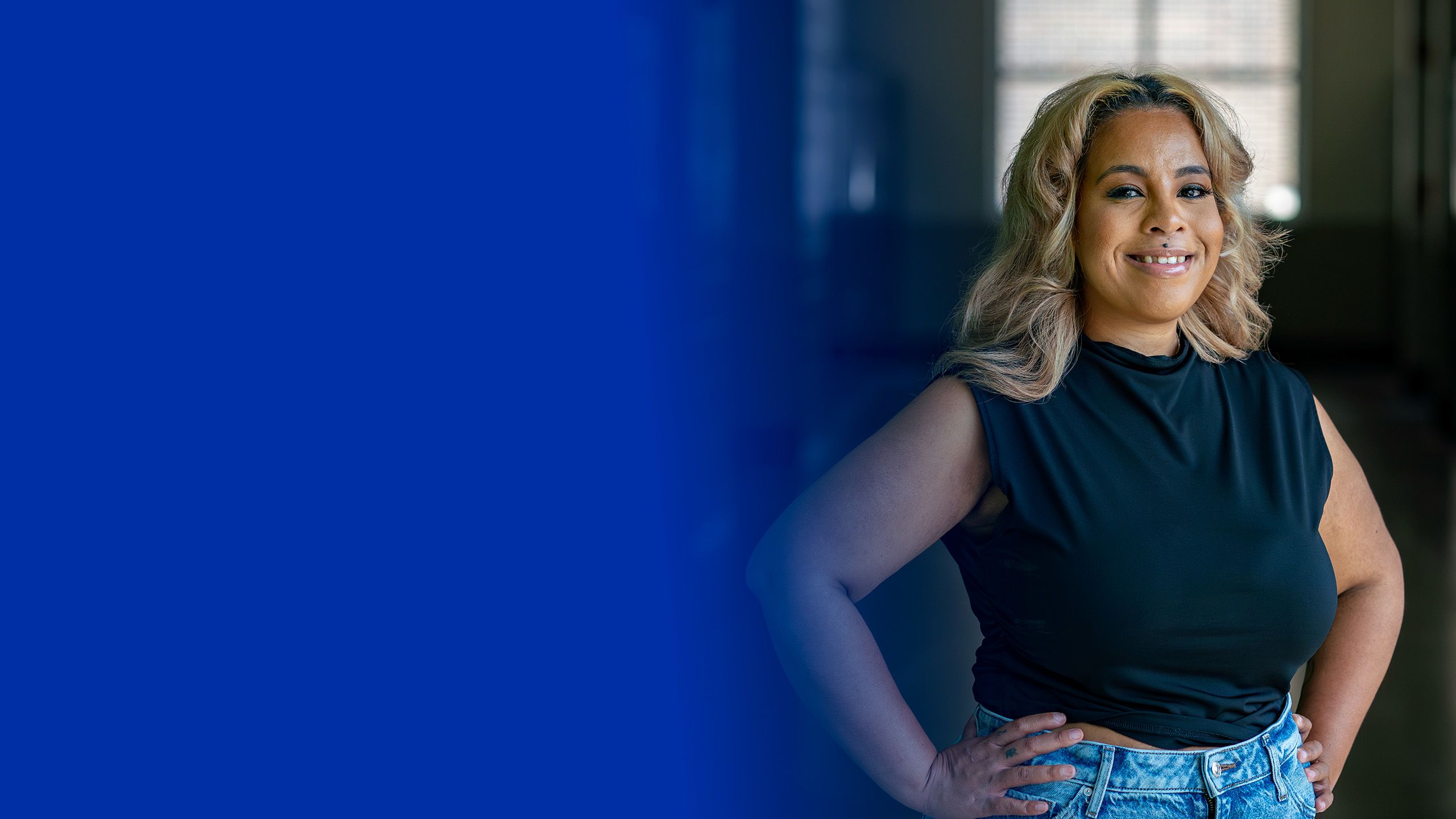 Khadijah Johnson stands with arm resting on railing, black top, small tattoos on two of her fingers