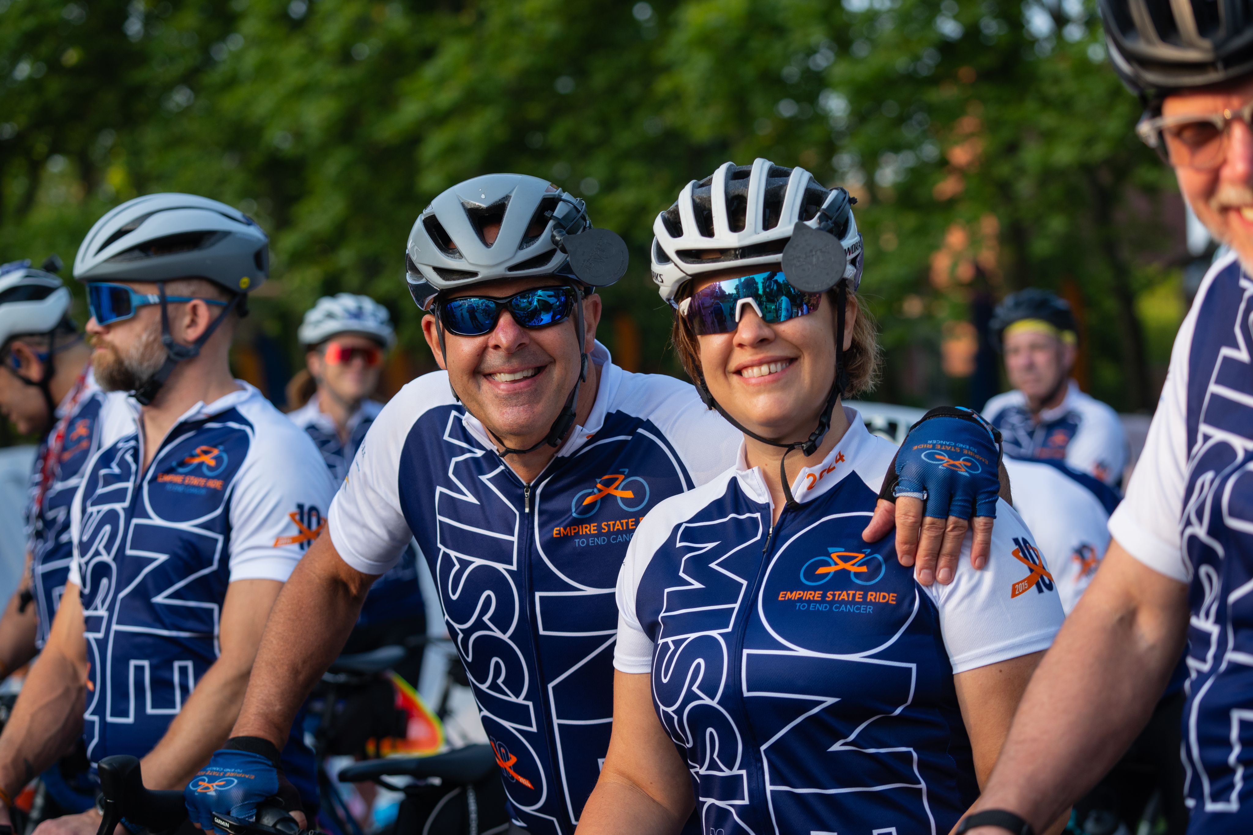group of bikers standing, wearing helmets and same bicycle shirts, mission one