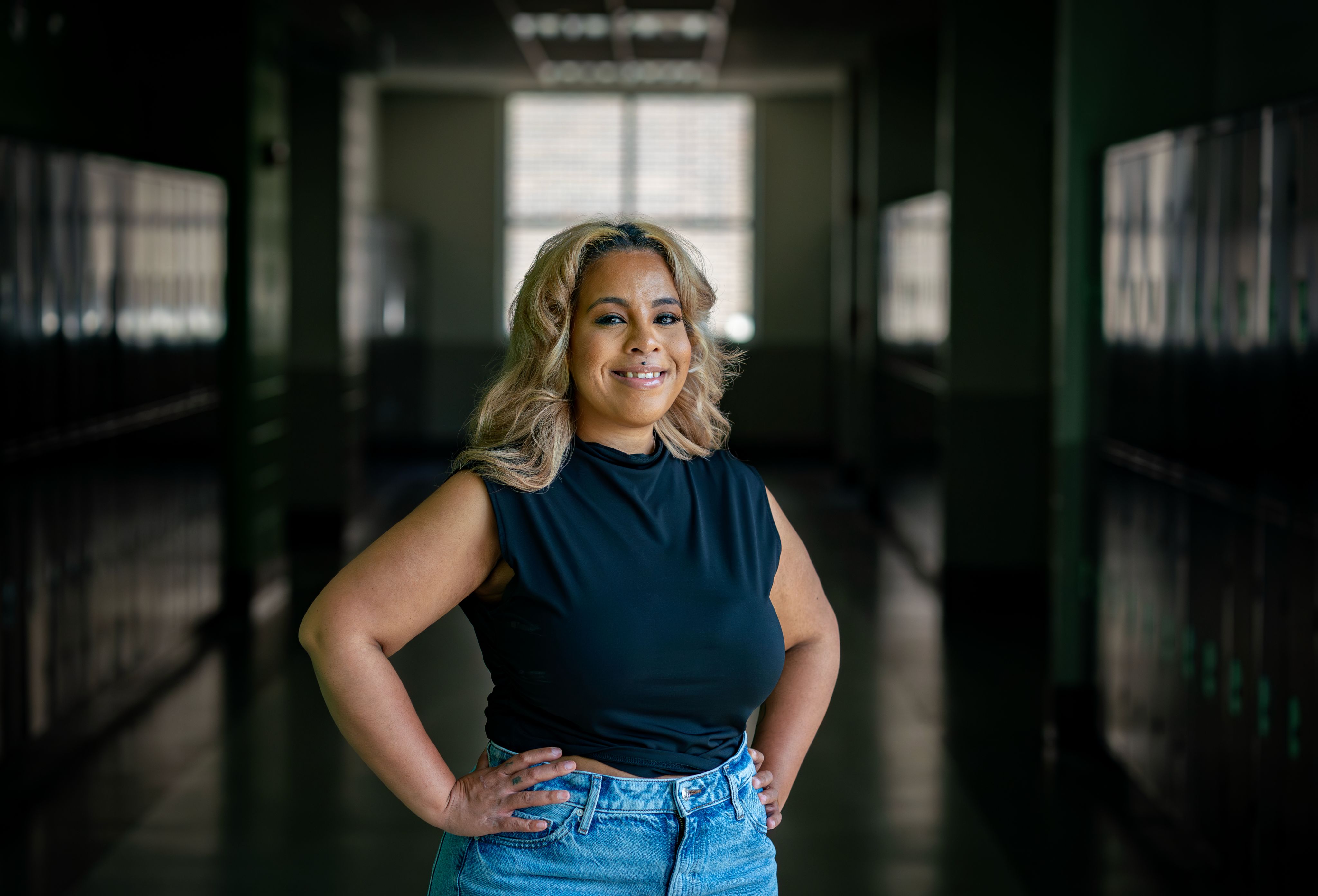 Khadijah Johnson stands with arm resting on railing, black top, small tattoos on two of her fingers