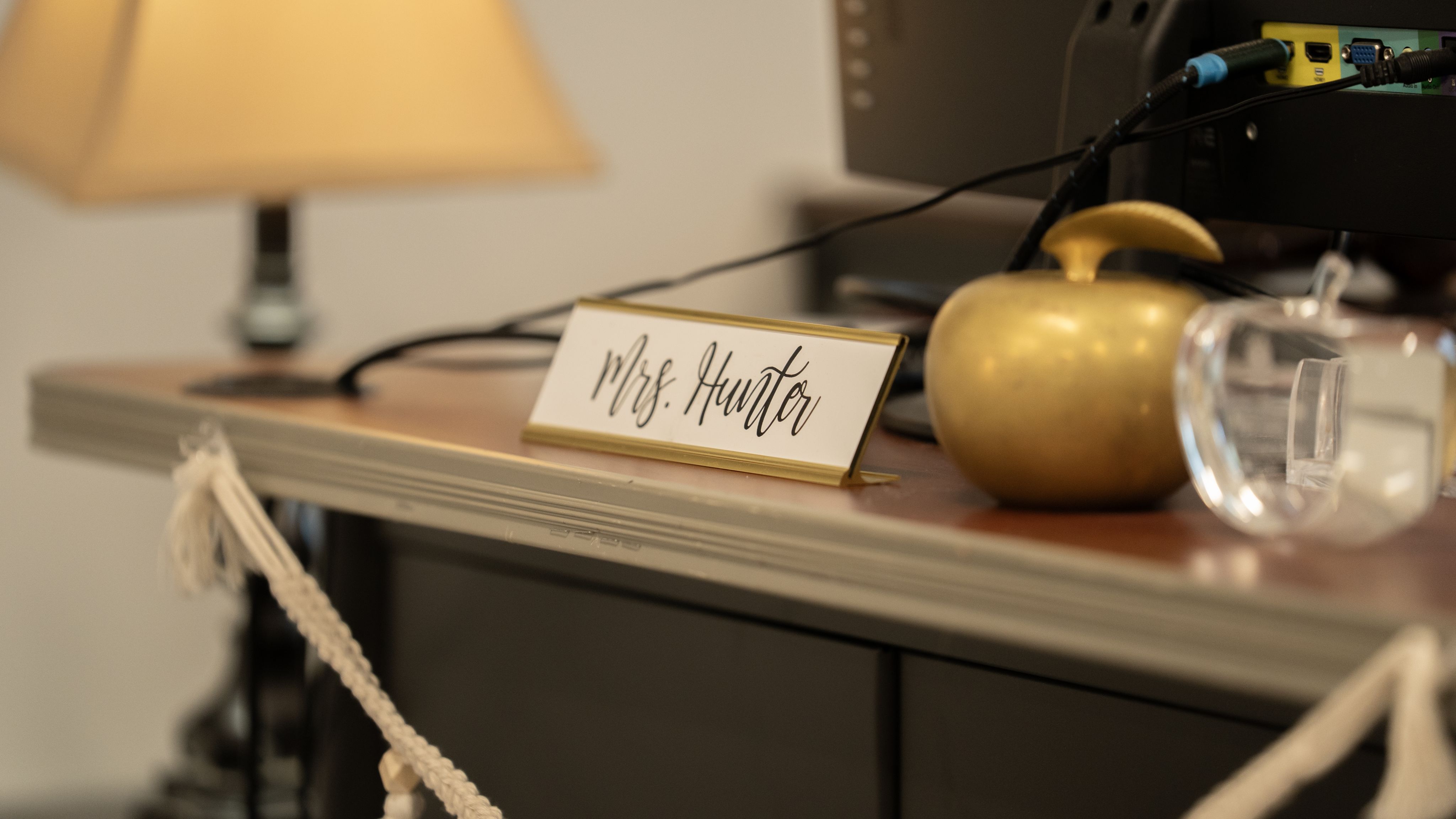a desk with Mrs. Hunter, and decorative apples in front of desktop